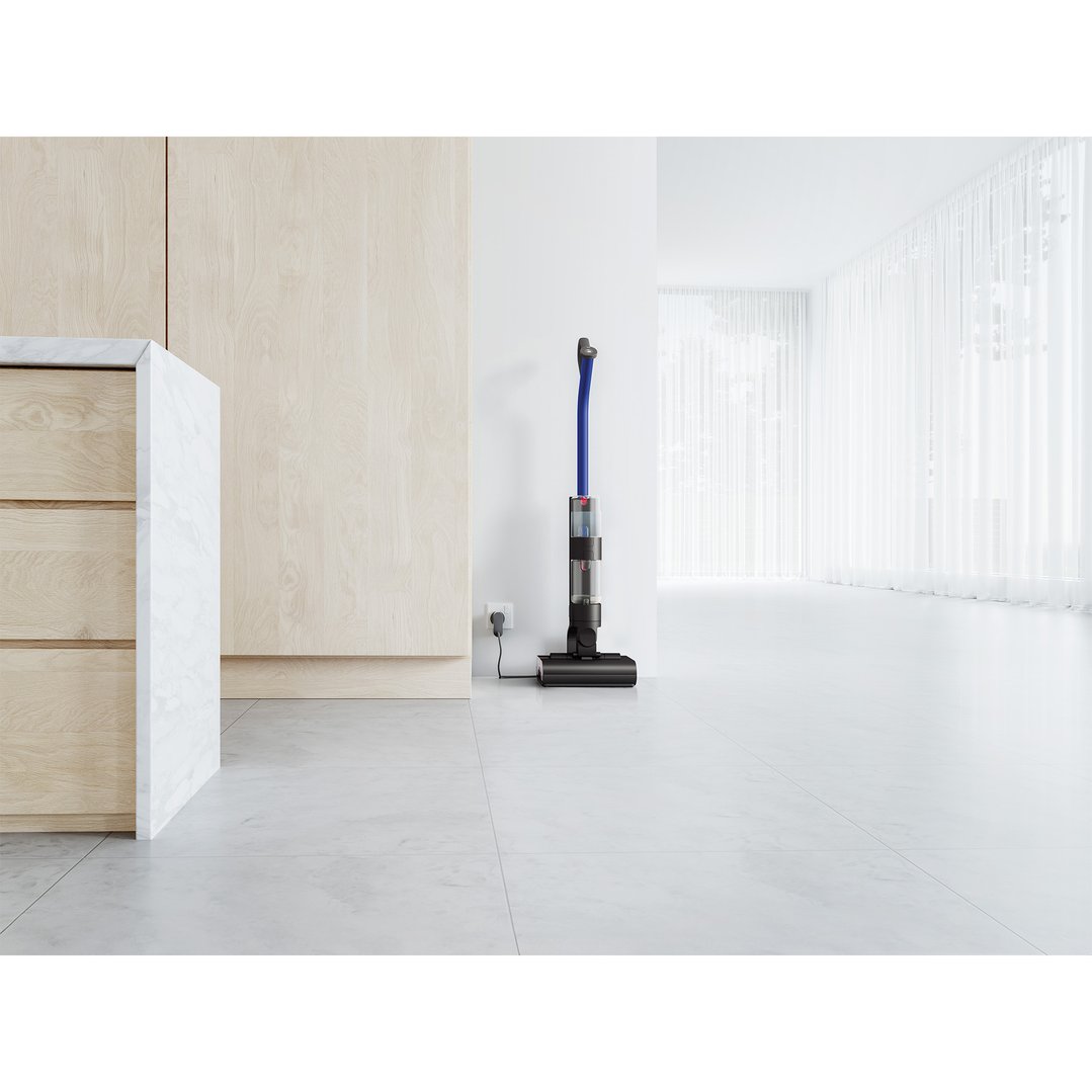 Dyson WashG1 wet cleaner charging in a modern room with light wood cabinetry