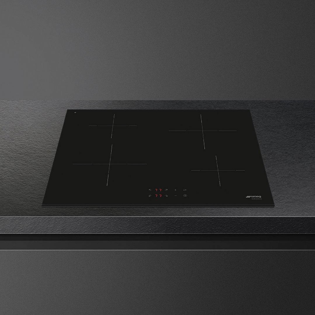 Black induction cooktop with four cooking zones on a dark countertop