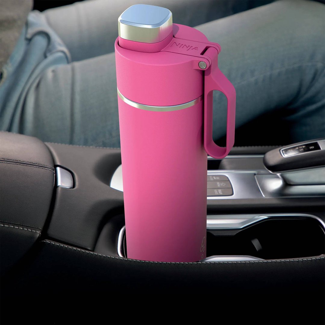 Pink Ninja Thirsti travel bottle in a car's cup holder