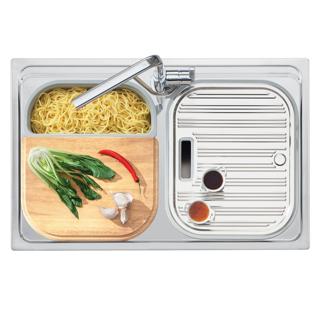 Overhead view of a double bowl sink with noodles, vegetables, and sauces