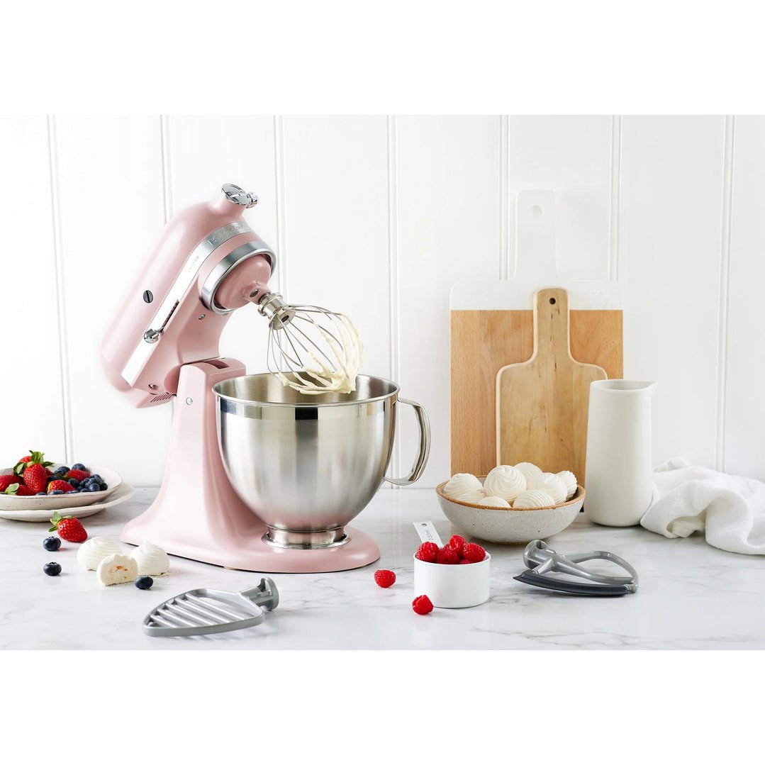 Pink KitchenAid stand mixer with whisk attachment mixing in a styled kitchen