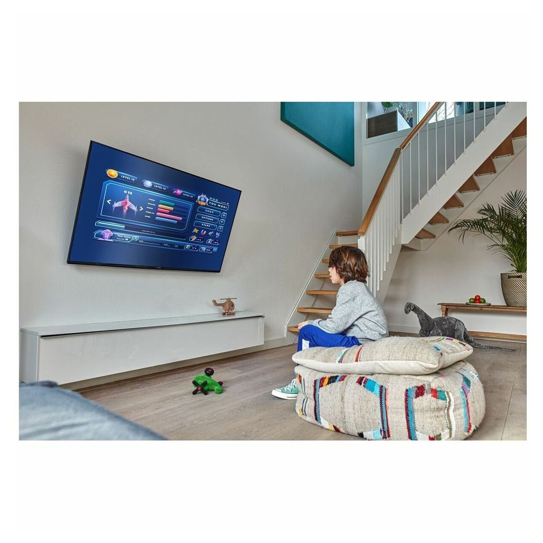 Child playing a video game on a wall-mounted TV in a living room