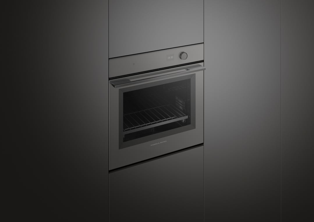 Built-in dark grey oven with its door slightly ajar in a dark kitchen