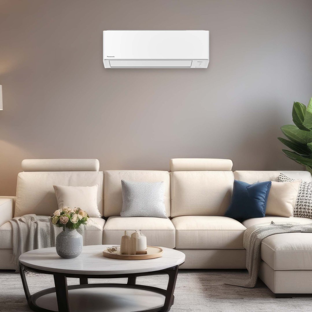 White Panasonic air conditioner mounted on a wall above a cream sofa