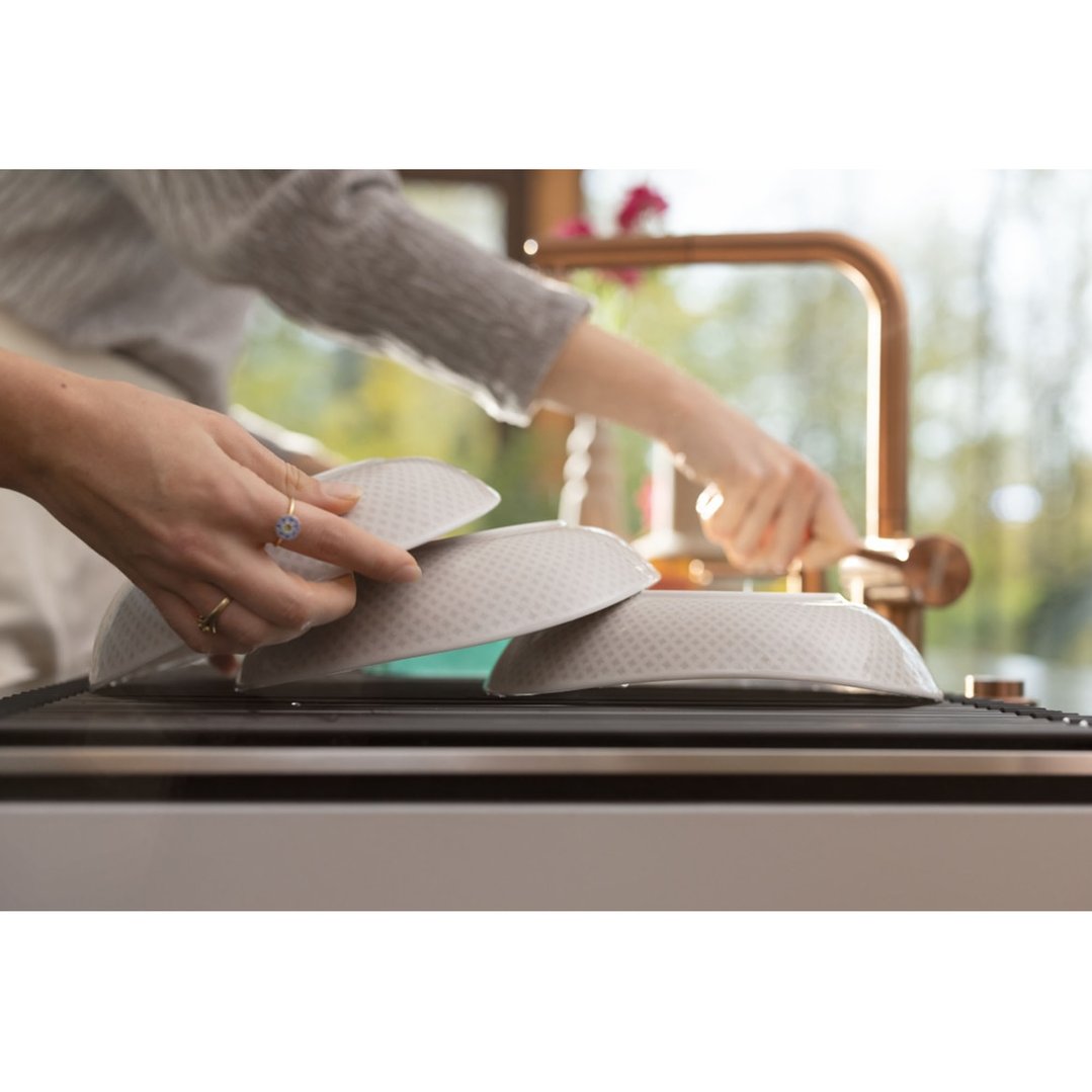 Hands placing dishes on a rolling mat in a kitchen setting