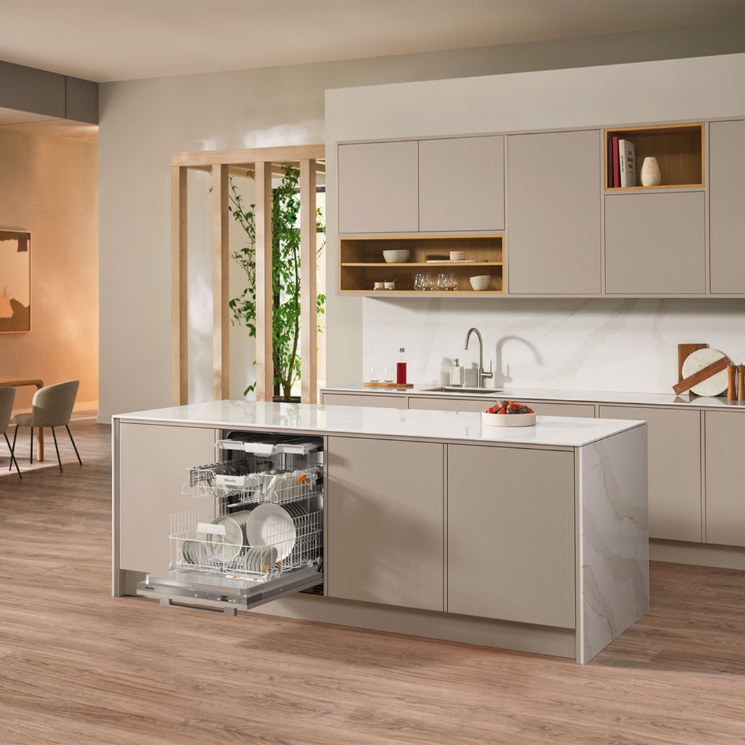 Fully integrated dishwasher open in a modern kitchen island with dishes inside