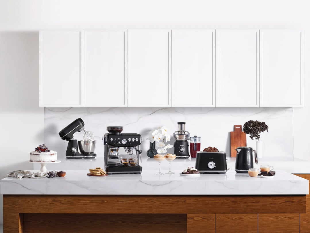Black Breville Barista Express Impress coffee machine and other appliances on a kitchen counter