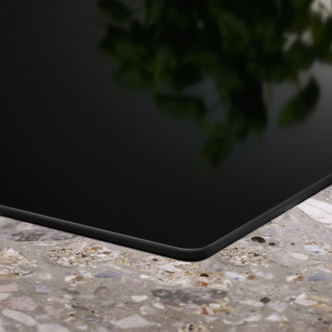 Close-up of a black induction cooktop installed in a speckled countertop