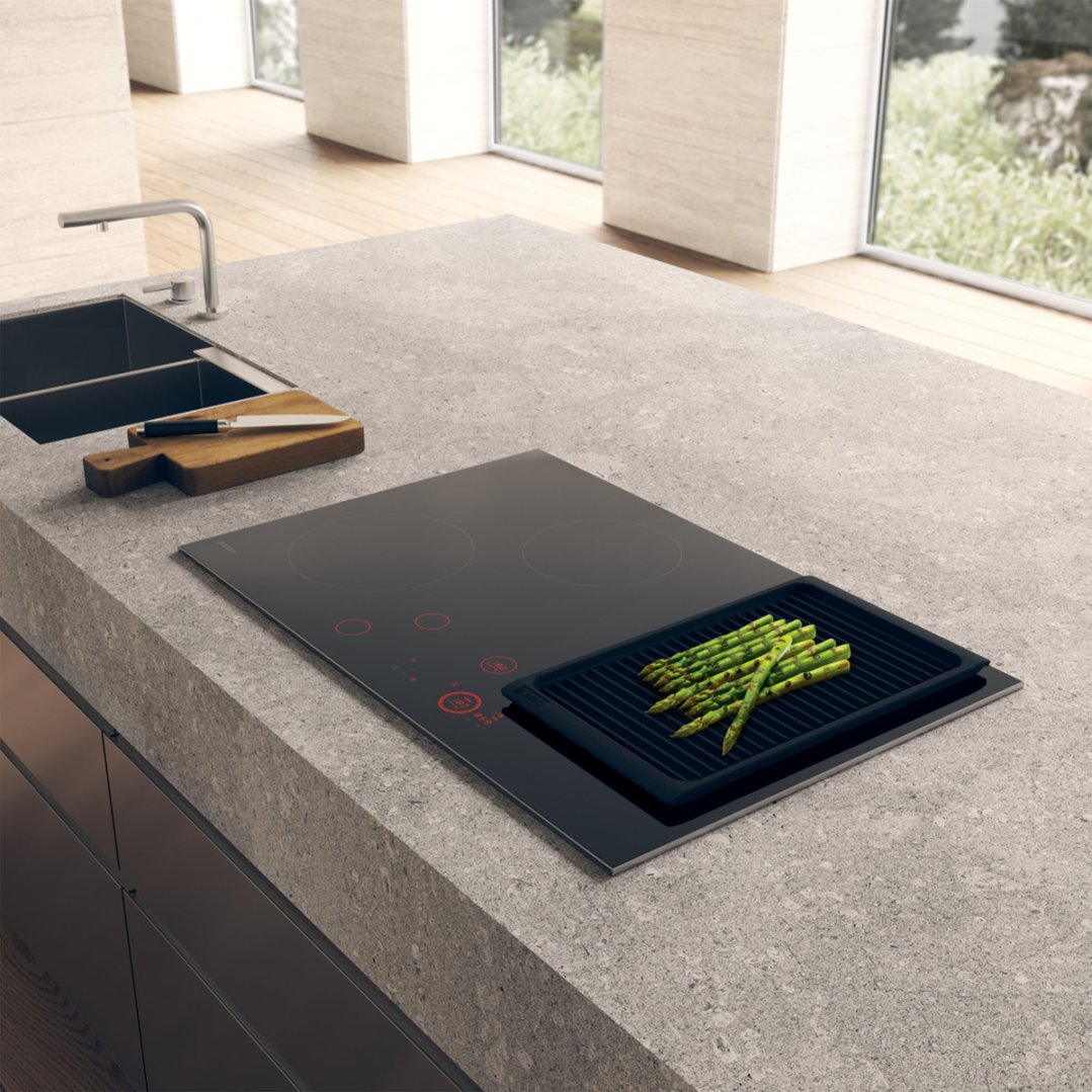 Induction cooktop with grill pan and asparagus in a modern kitchen setting