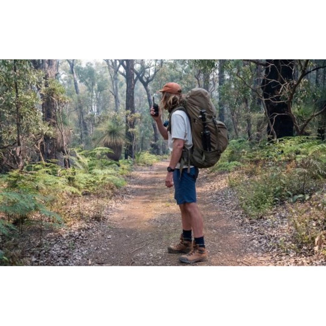 Man holding a 5 Watt UHF CB Splashproof Handheld Radio on a forest path