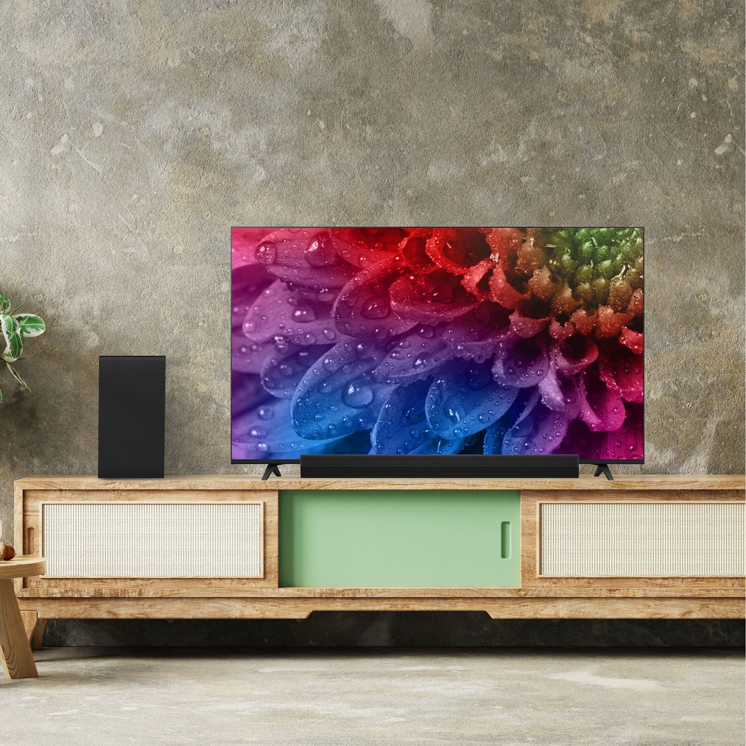 LG sound bar and subwoofer on a wooden cabinet with a TV