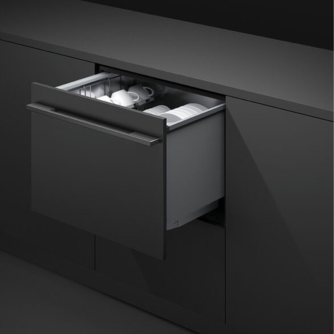 Open integrated DishDrawer dishwasher with dishes inside a dark kitchen