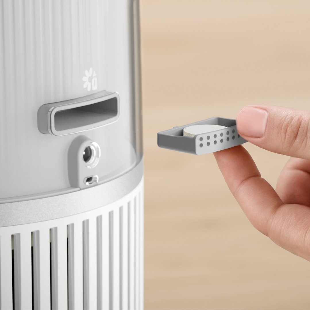 Hand inserting an aroma diffuser tray into the side of a humidifier