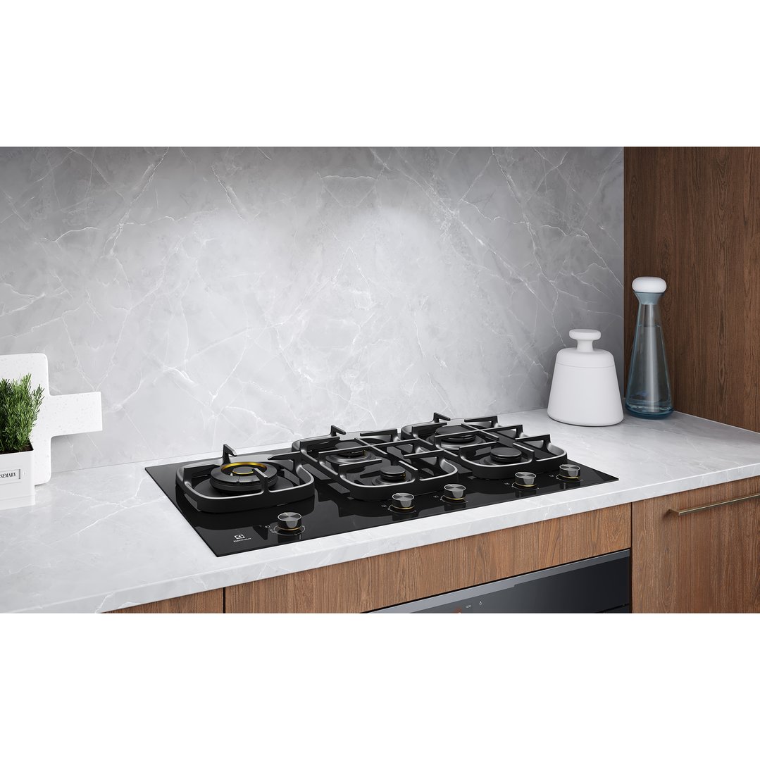 Black 5-burner gas cooktop installed in a modern kitchen with marble backsplash