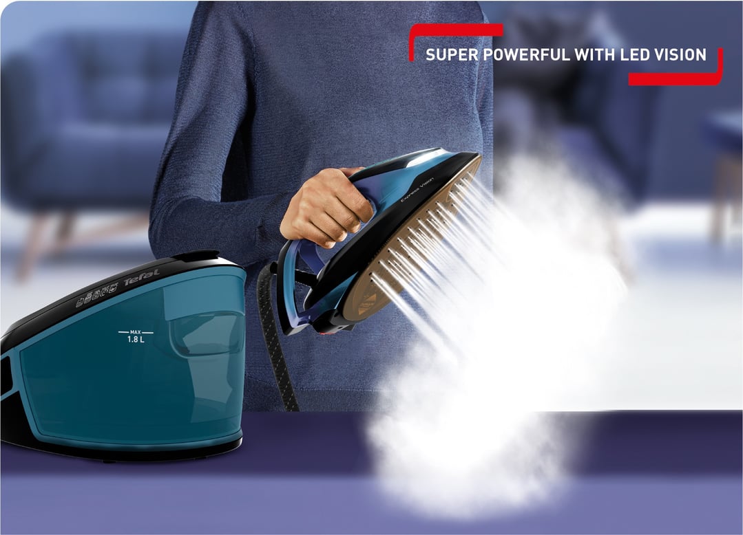 Person holding a steam station iron, releasing steam, with the water tank visible