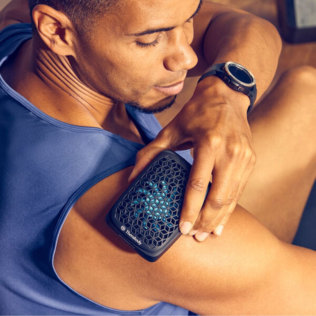 Man using a black Therabody massager on his bicep
