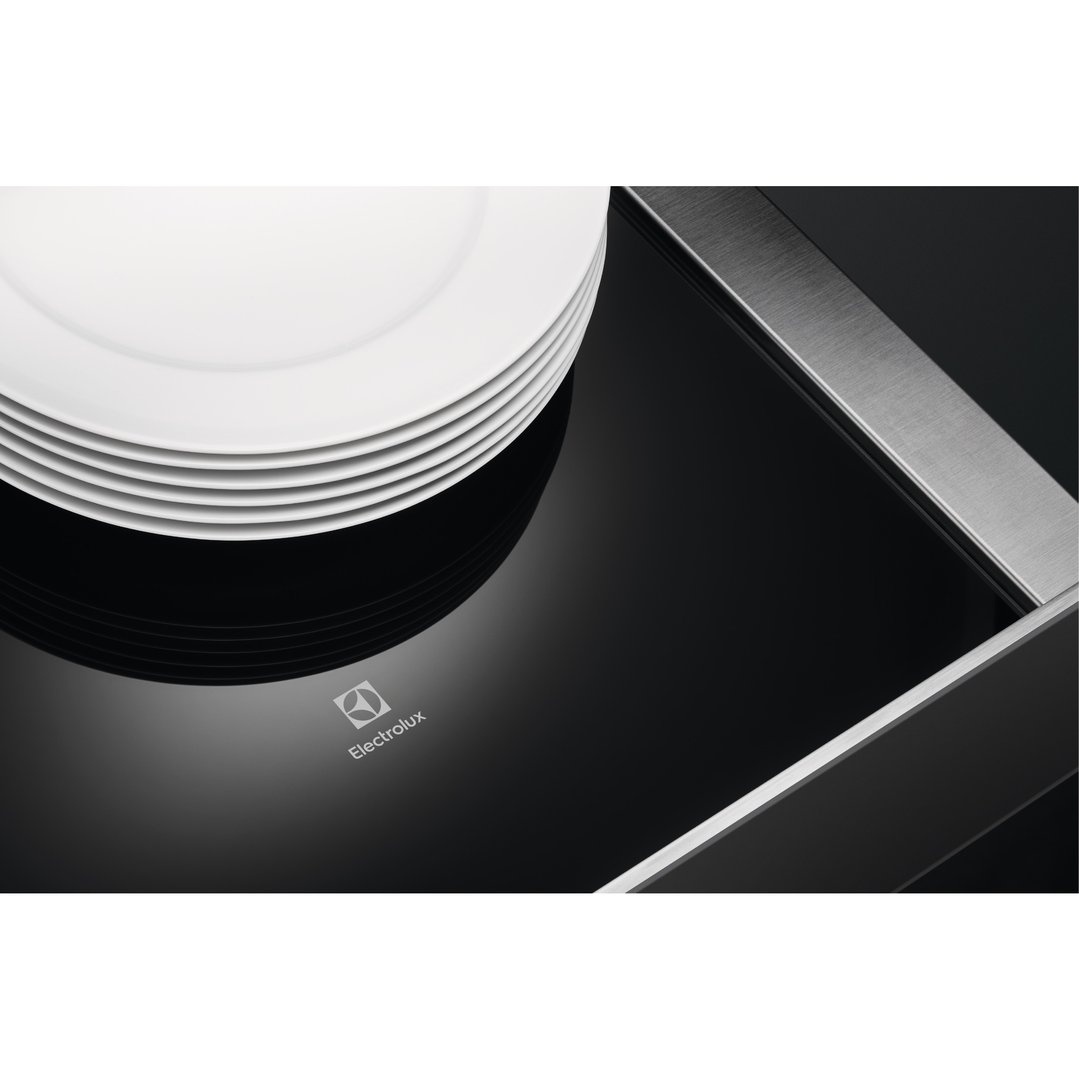 Stack of white plates on a black warming drawer with a metallic trim