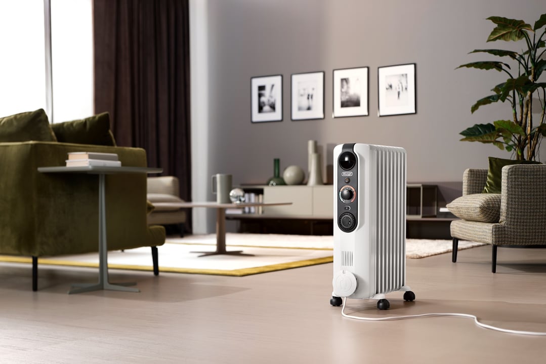 White oil column heater in a modern living room with green and grey furniture