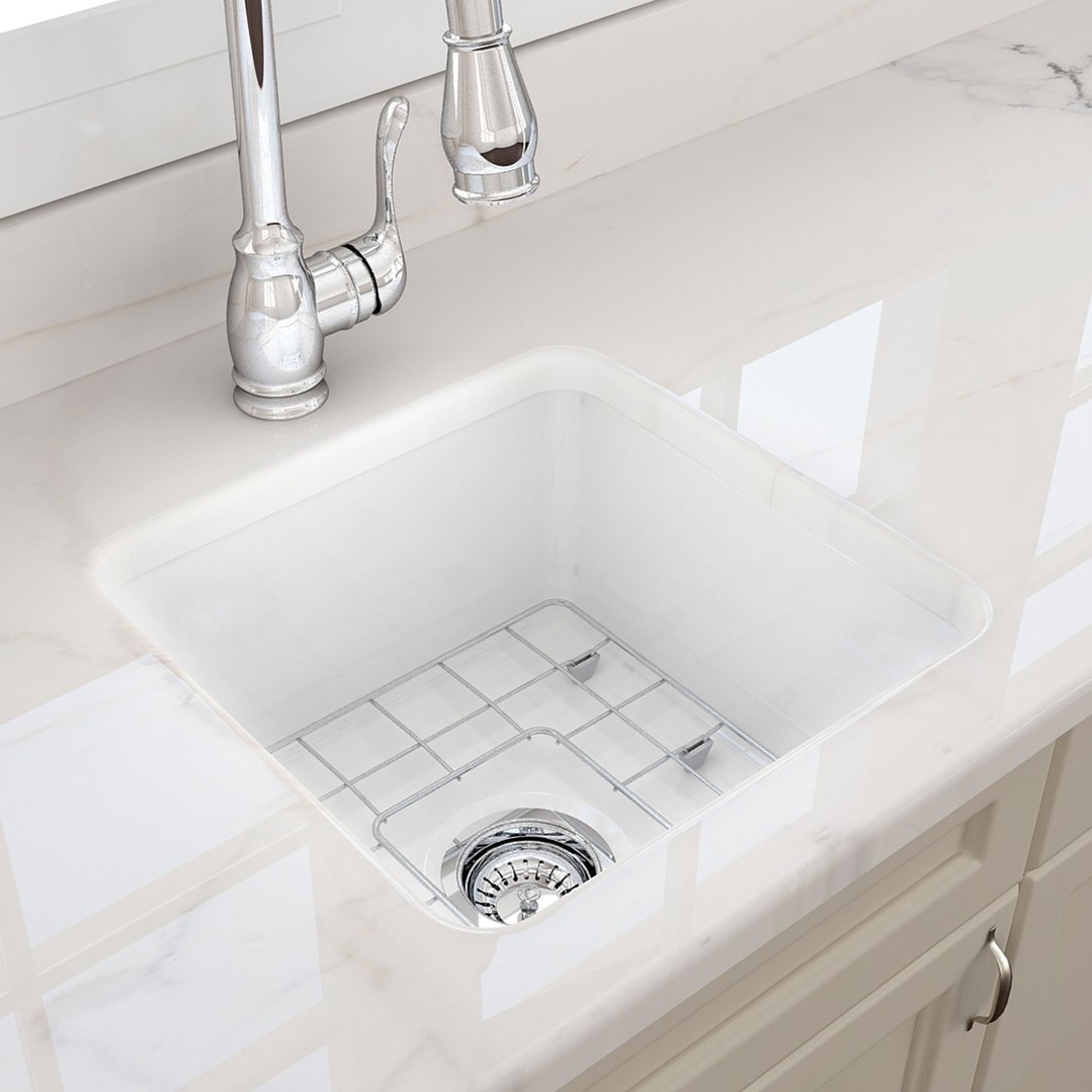 White fireclay sink with a chrome faucet and grid in a kitchen setting