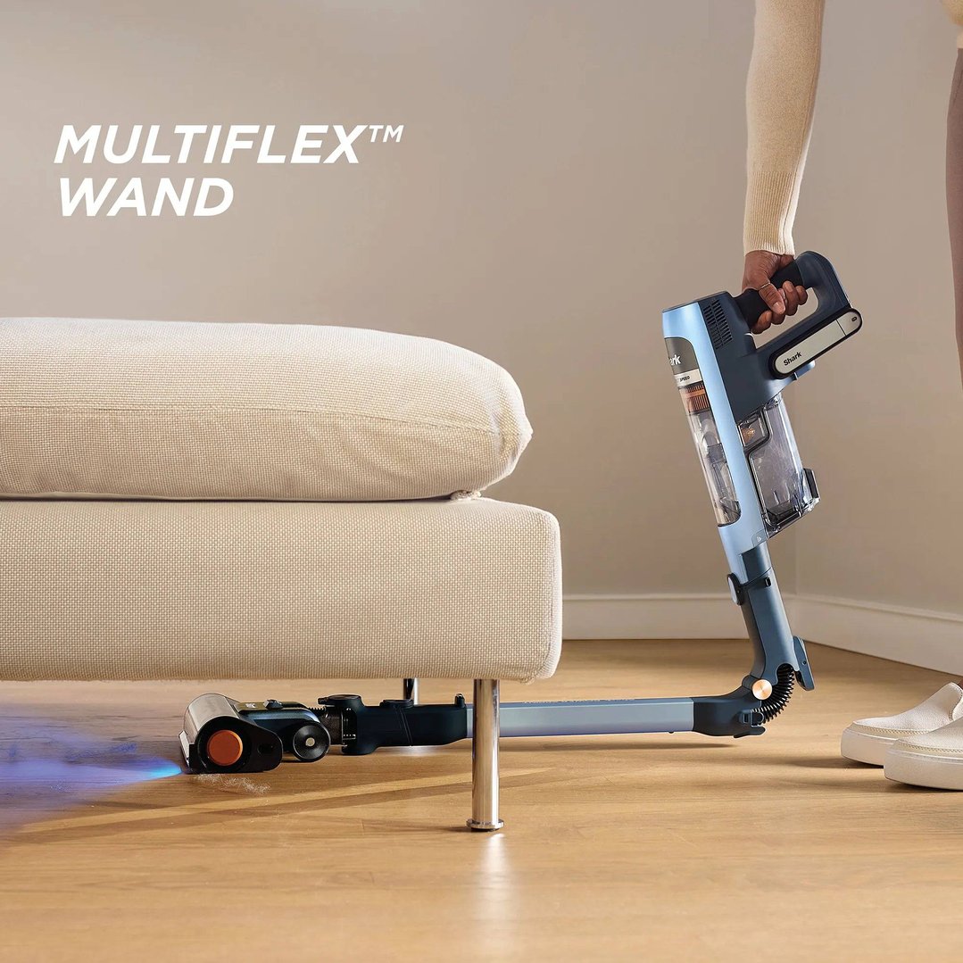 Person using a Shark handstick vacuum to clean under a sofa