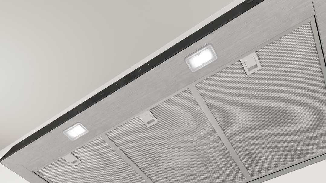 Underside view of a stainless steel rangehood with lights and filters