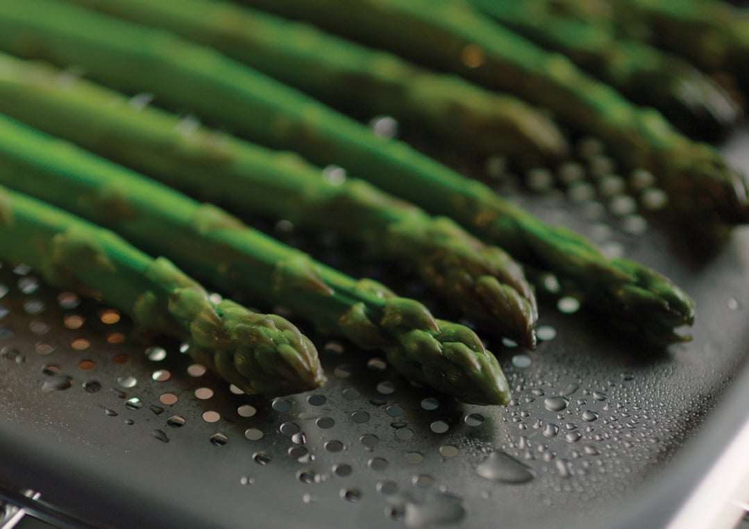 Close up of asparagus spears on a perforated tray in a steam oven