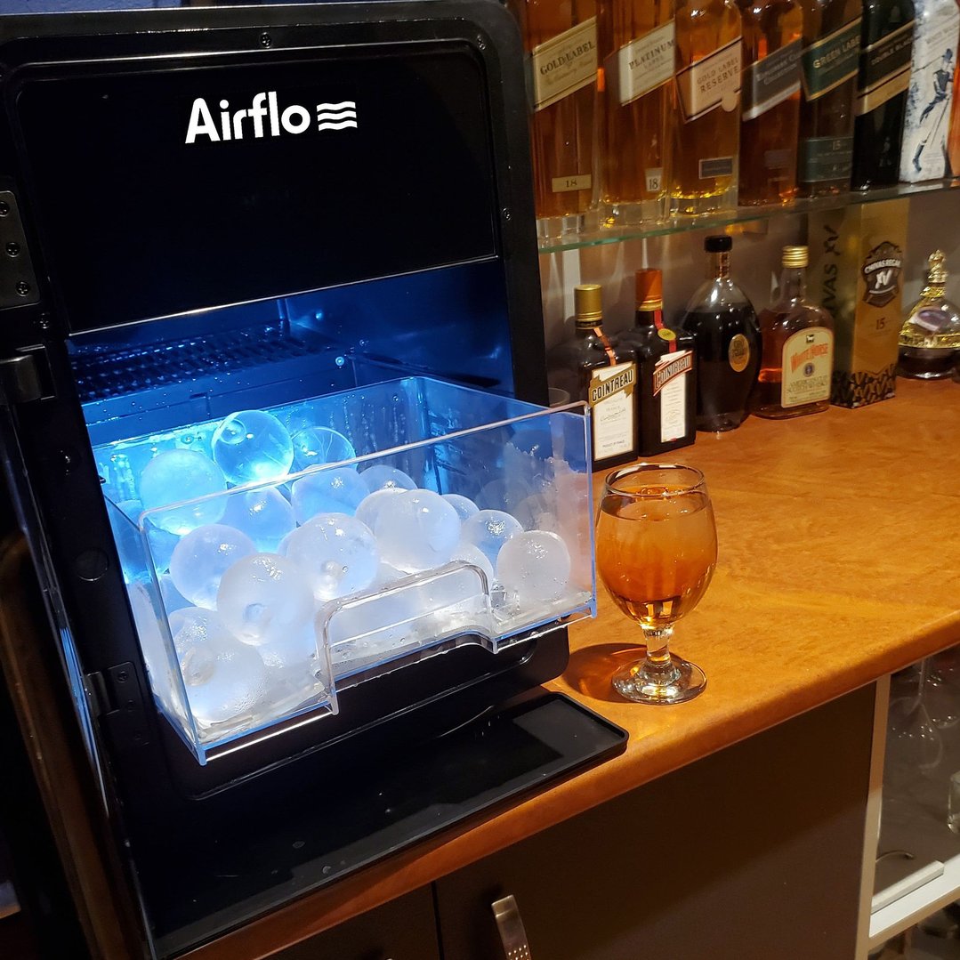 AIRFLO Sphere Ice Maker with ice spheres and a drink on a bar counter