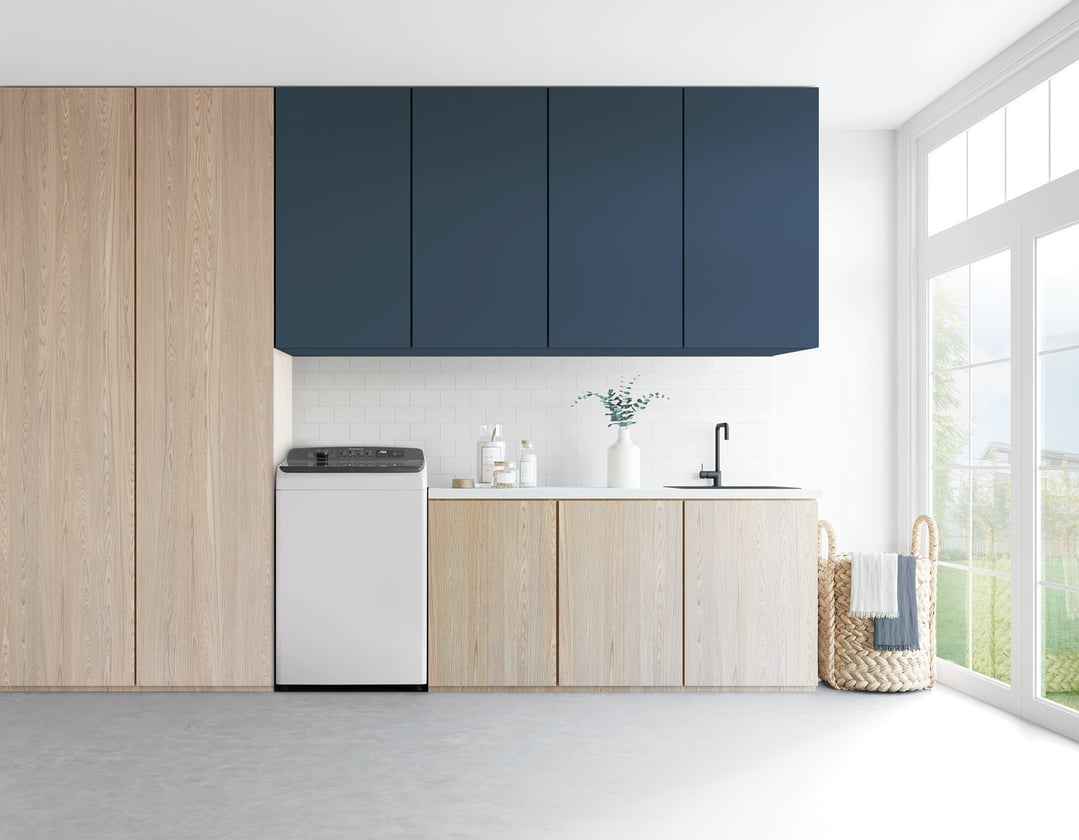 Top load washer in a modern laundry room with wood and blue cabinets