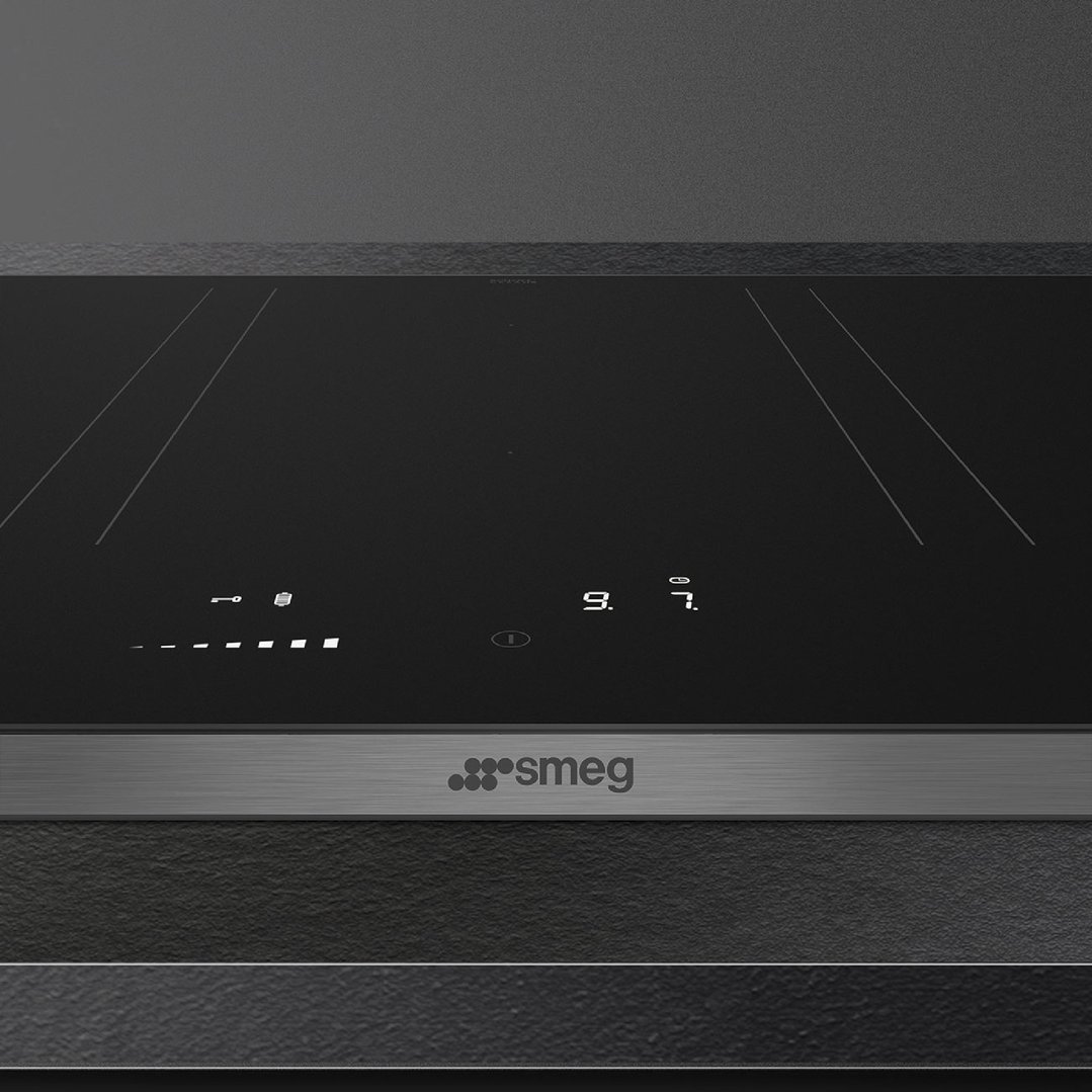 Close up of a black induction cooktop with digital controls and Smeg logo