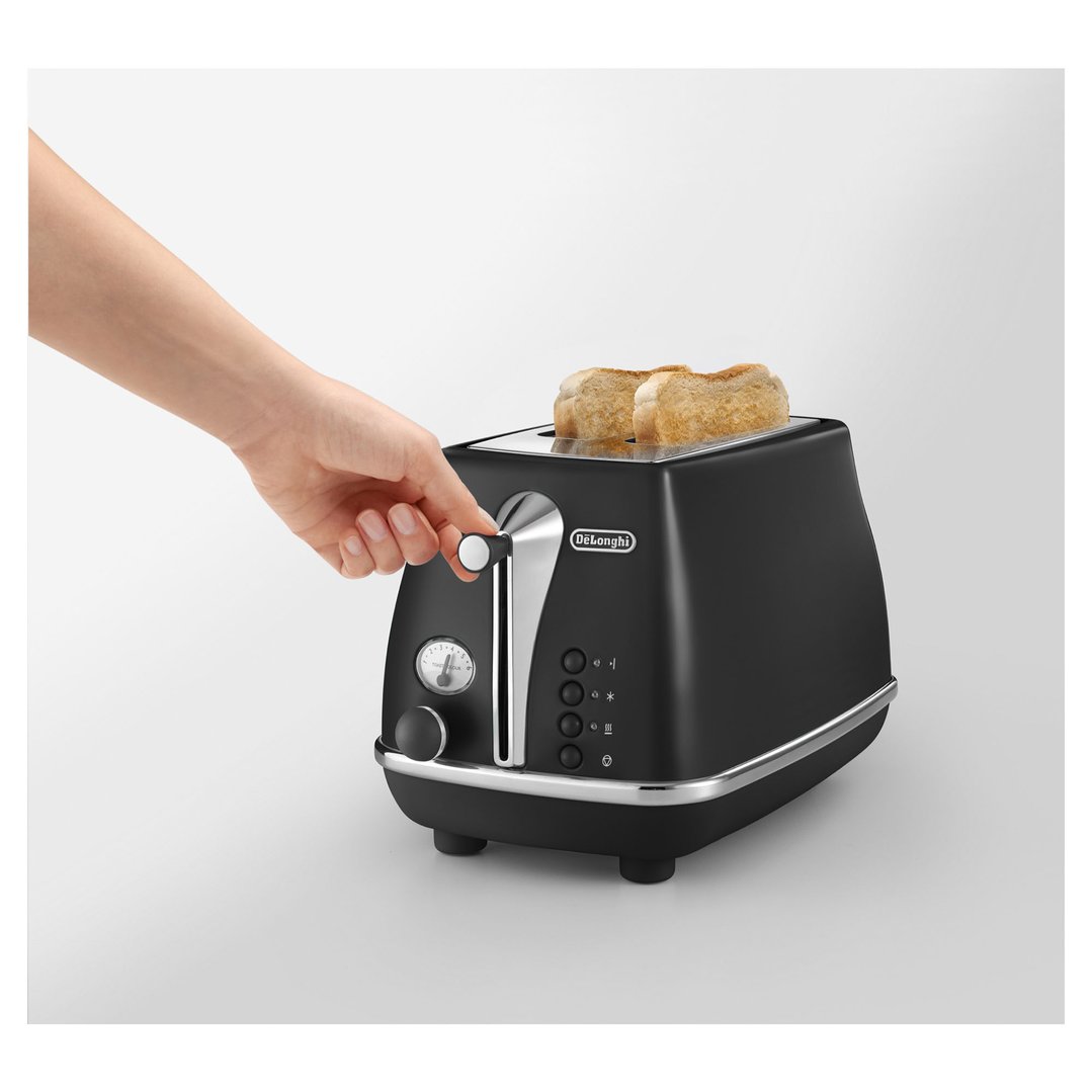 Hand adjusting the toast colour dial on a black DeLonghi toaster with toast
