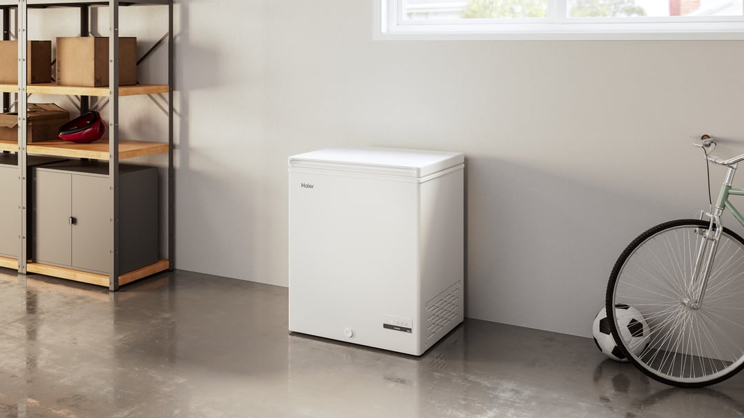 White Haier chest freezer in a garage with shelving and a bicycle