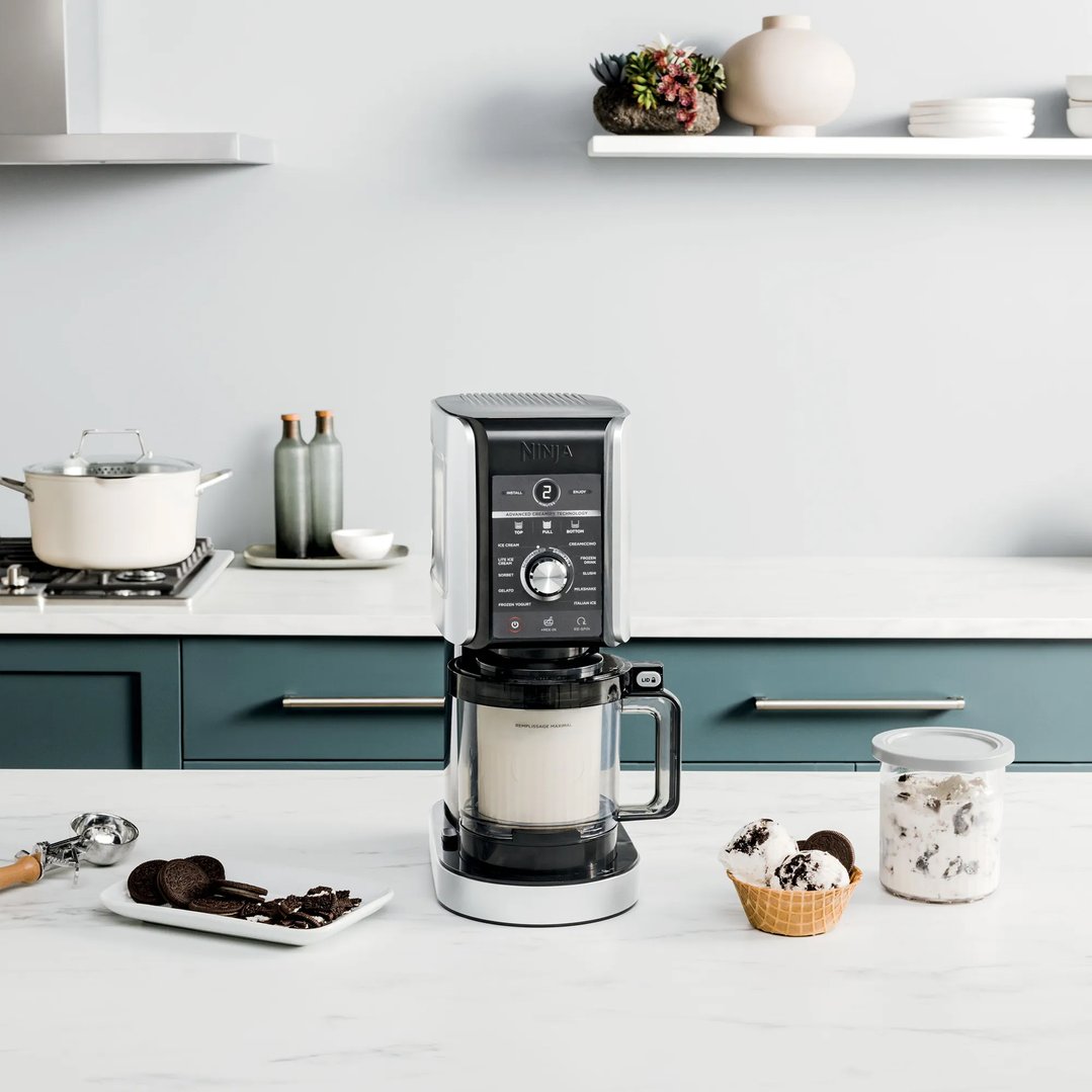 Ninja CREAMi Deluxe ice cream maker on a kitchen counter with ice cream