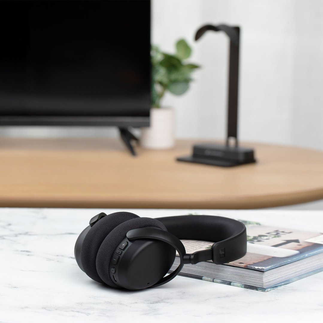 Black Sennheiser TV headphones on a book on a marble table