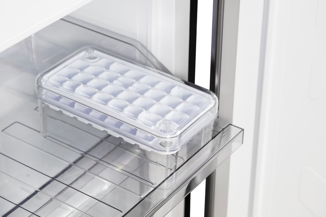Close up of an ice cube tray inside the open freezer compartment of a fridge