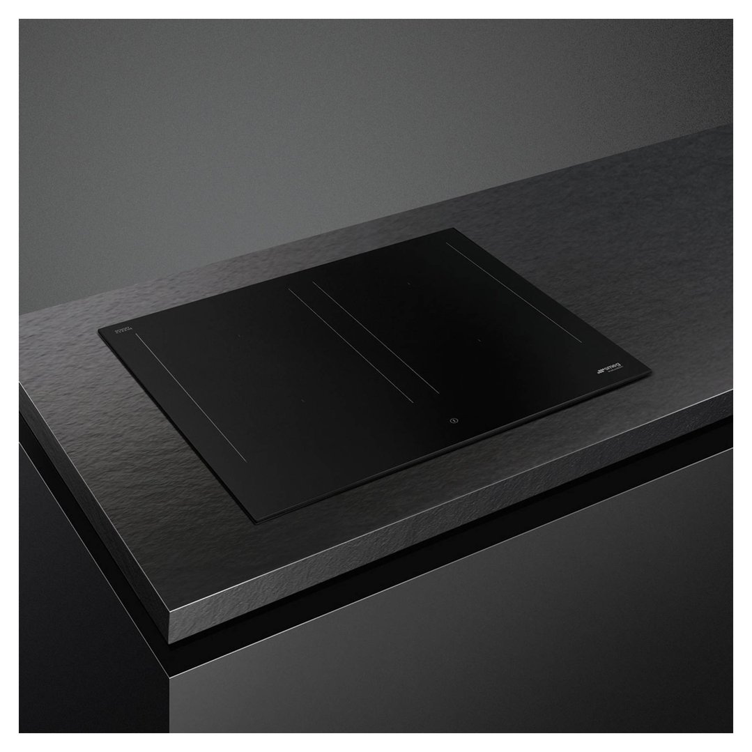 A black induction cooktop is built into a dark countertop in a modern kitchen