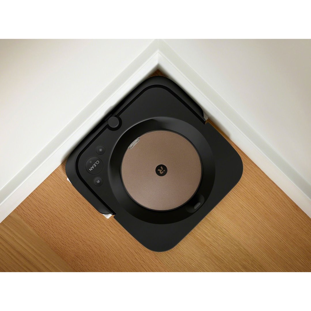 Black robot mop cleaning a wooden floor in a room corner
