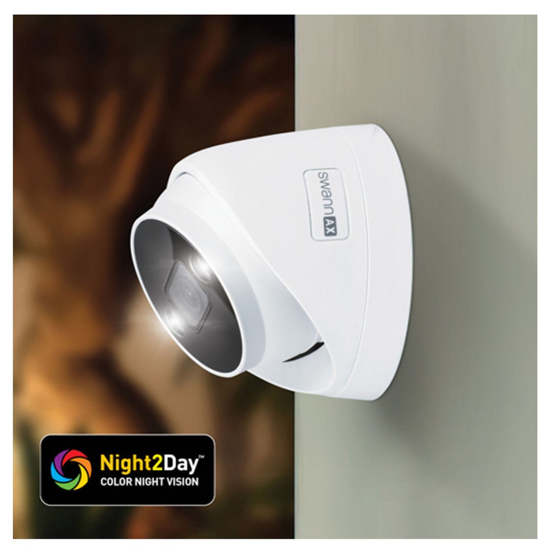 A white security camera mounted on a wall with a blurred background