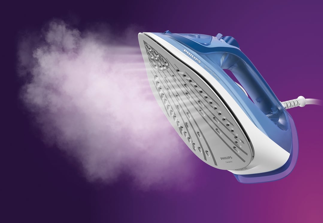 Blue Philips steam iron emitting steam on a purple background