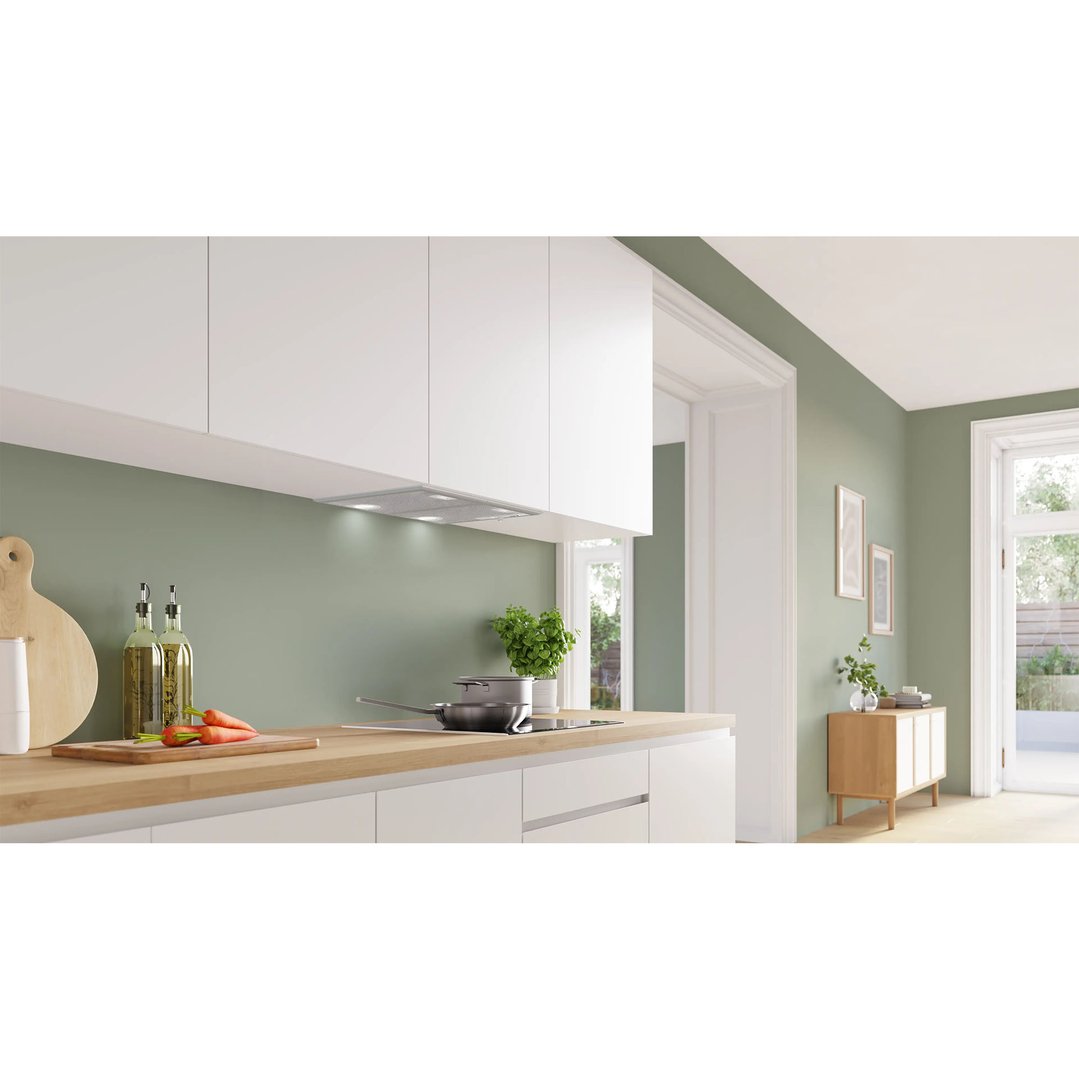 Integrated rangehood in a modern kitchen with white cabinets and wooden countertop