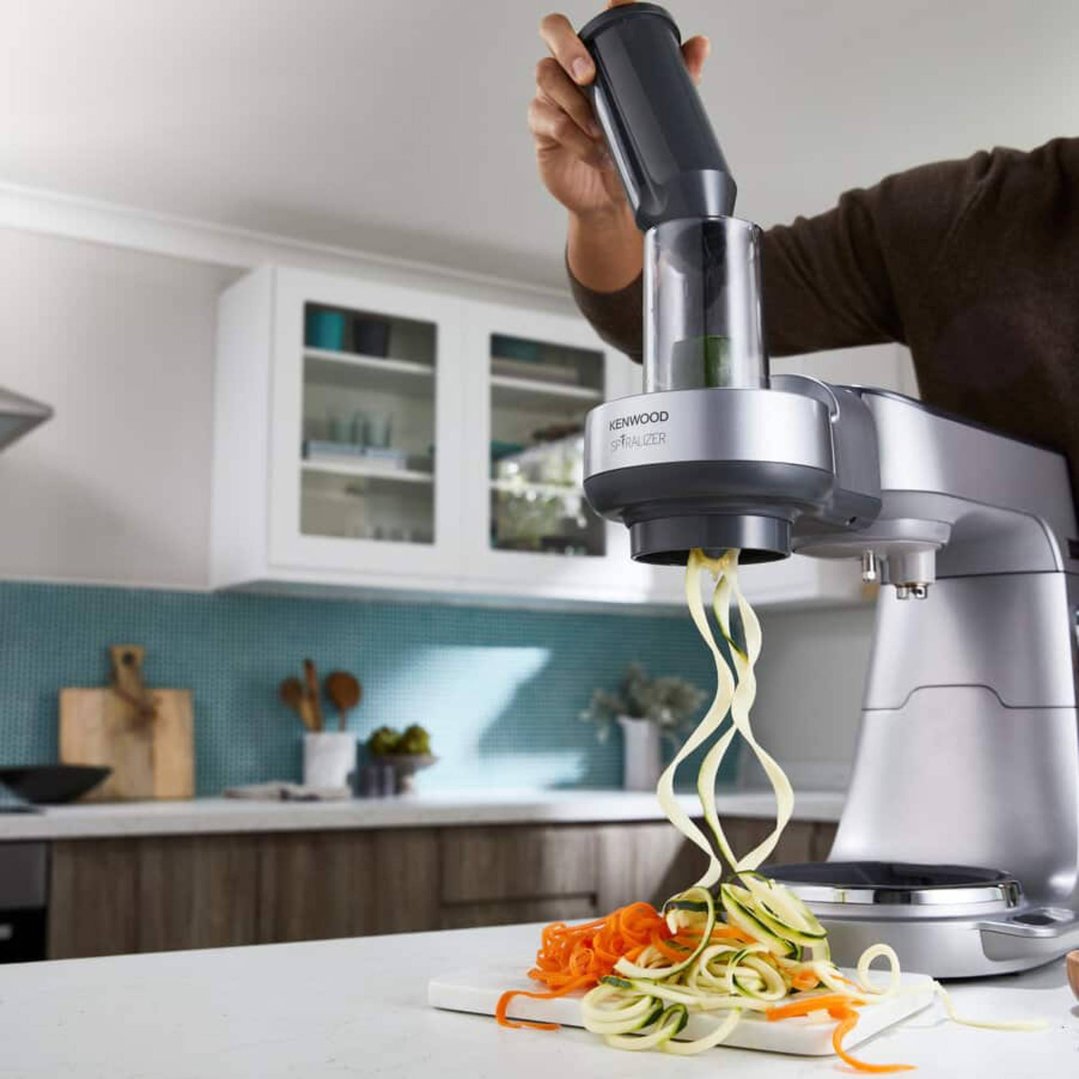 Person using a spiralizer attachment on a stand mixer to make vegetable noodles