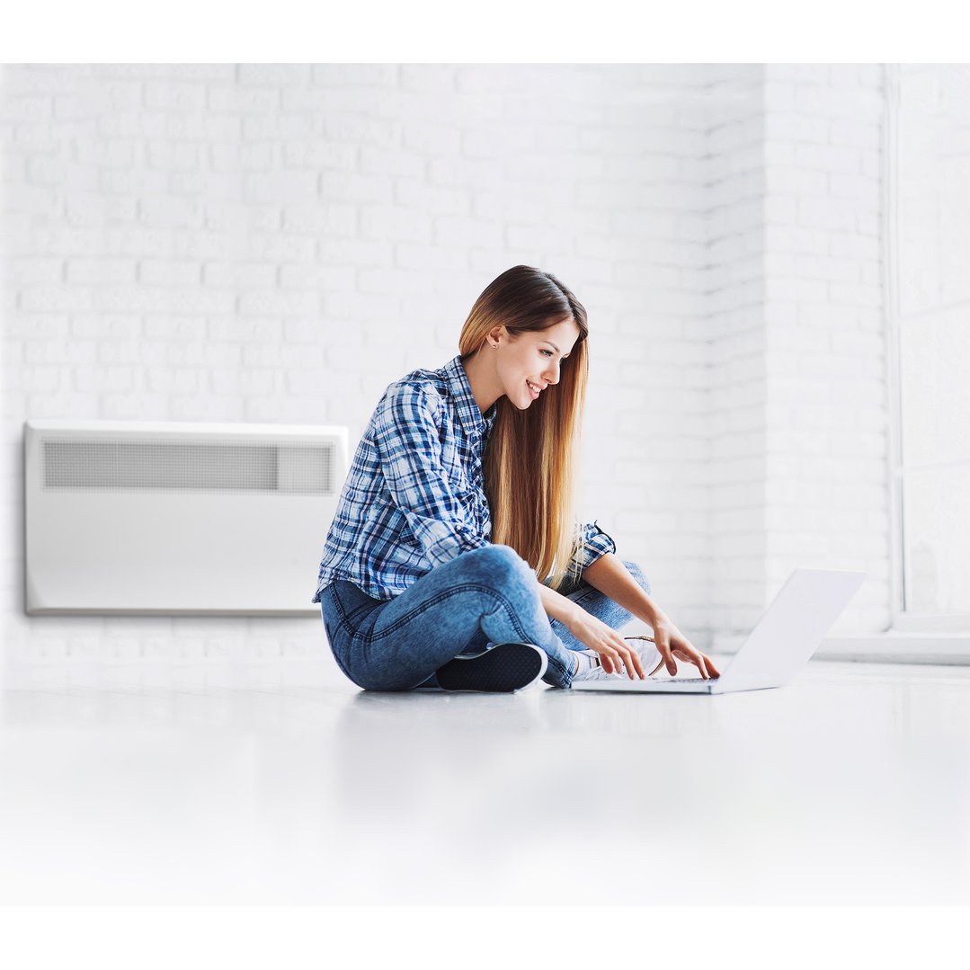 Woman sitting on the floor using a laptop with a Rinnai electric panel heater
