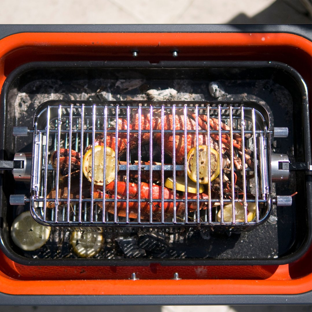 Rotisserie Cage with lobster and lemons cooking on a charcoal grill