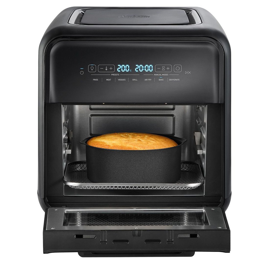 Black air fryer oven with door open, showing a cake baking inside