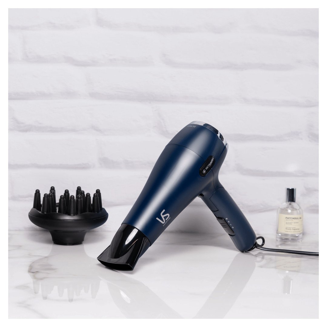 VS Sassoon hair dryer and diffuser on a marble surface with a white brick wall