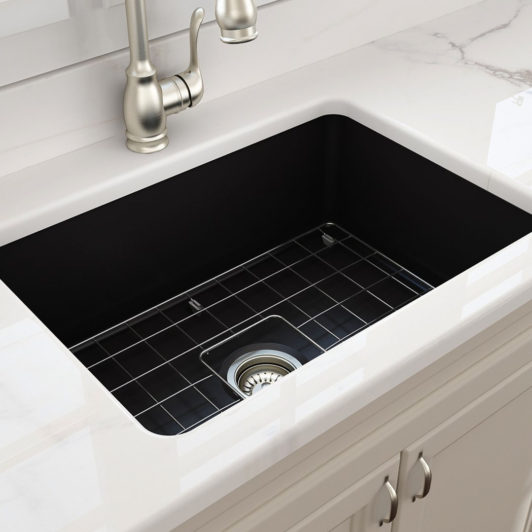 Matte black fireclay sink with a metal grid and faucet in a kitchen setting