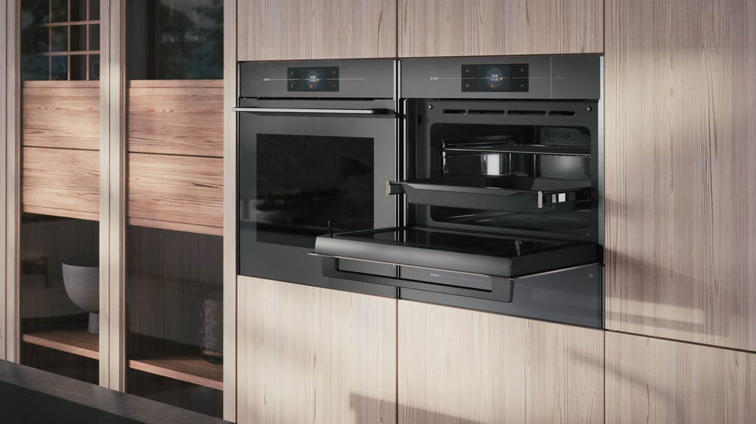 Two built-in ovens in a light wood kitchen cabinet, one open