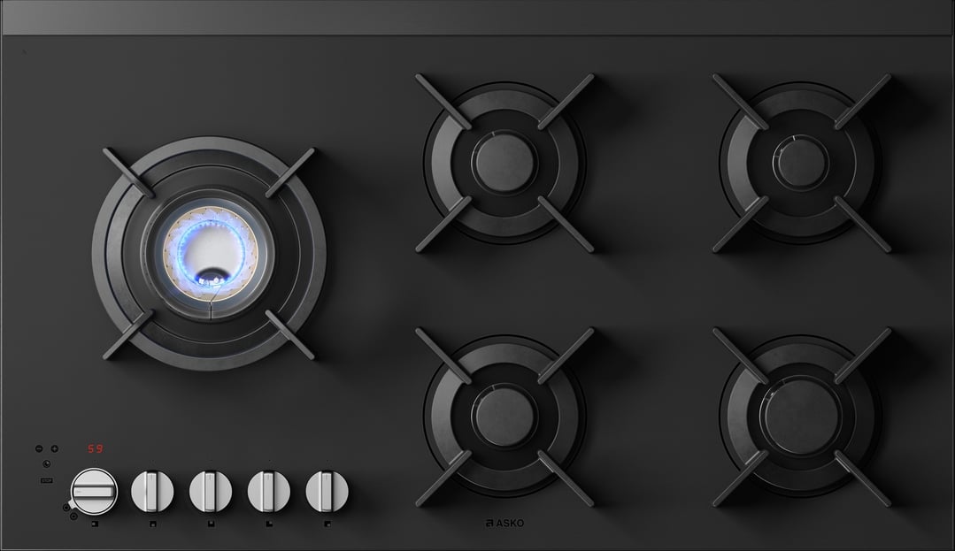 Overhead view of a black 5-burner gas cooktop with one burner lit