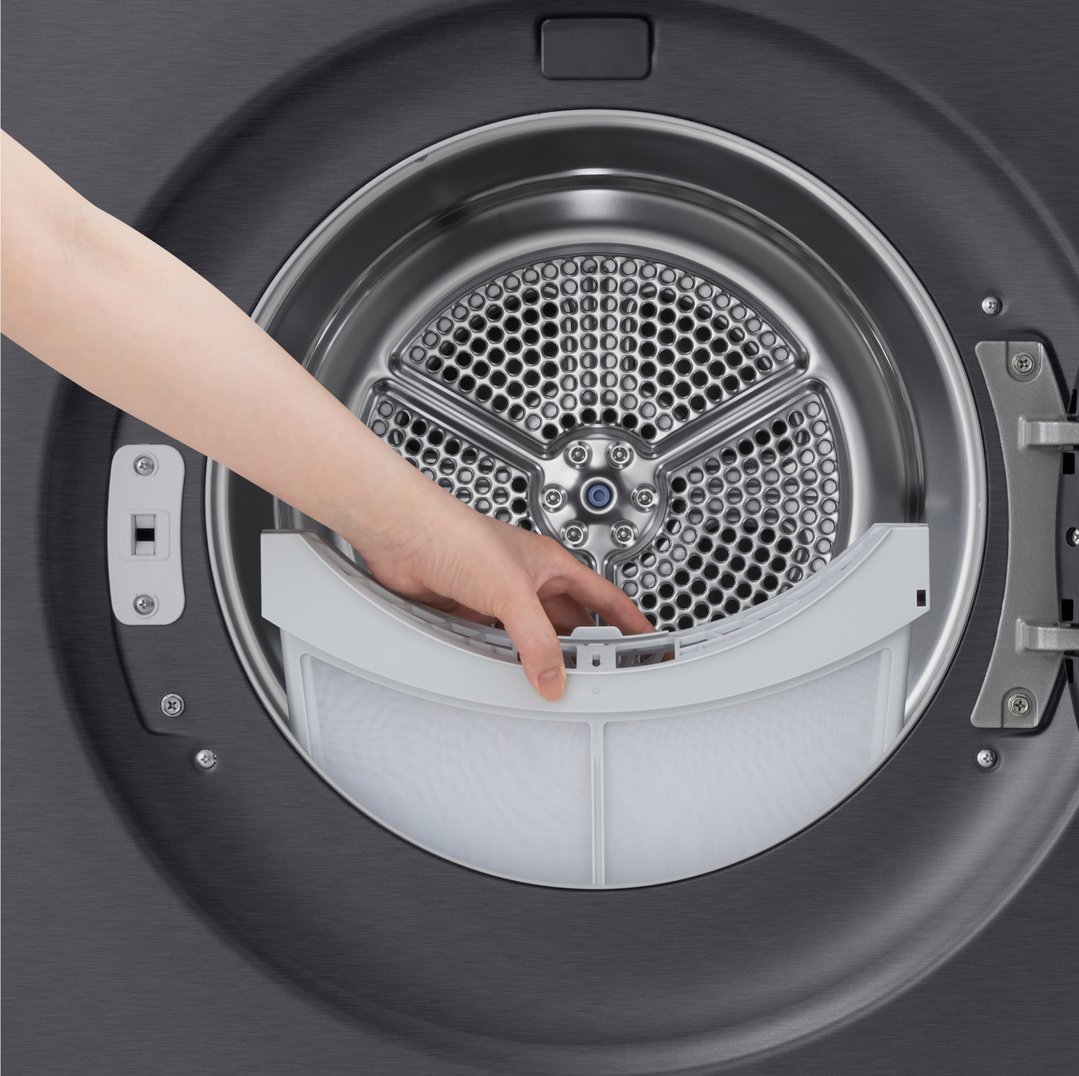 A hand removing the lint filter from inside a dark grey dryer