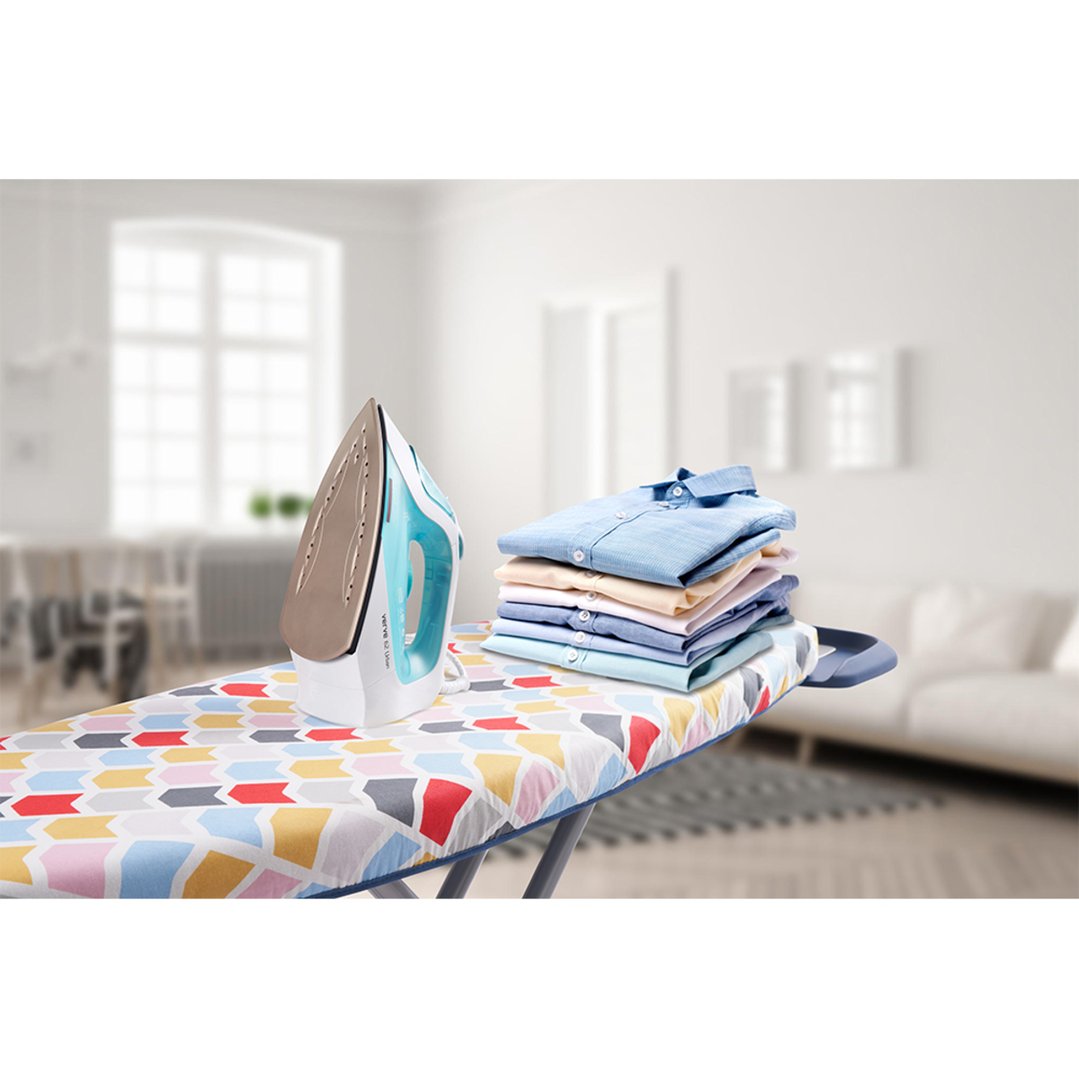 Ironing board with an iron and a stack of folded shirts in a living room