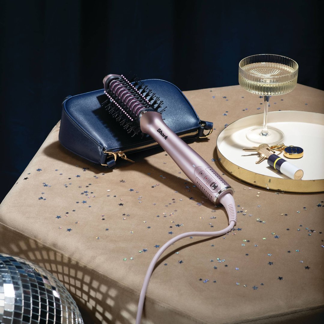 Shark Glossi 2-in-1 Hot Tool & Air Glosser on a table with a drink